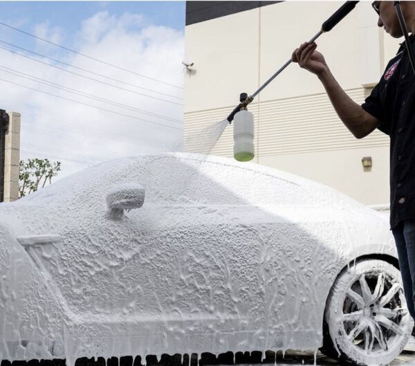 A man is washing his car with a hose.