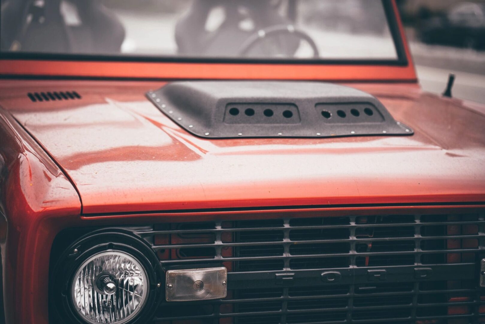 A close up of the hood on an old red car