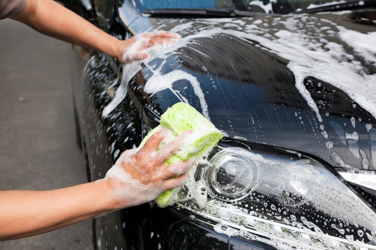 A person washing a car with a sponge