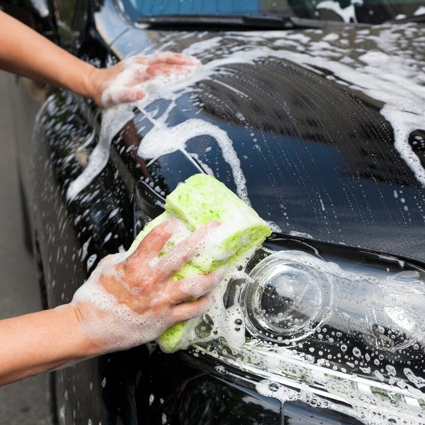 A person washing a car with a sponge